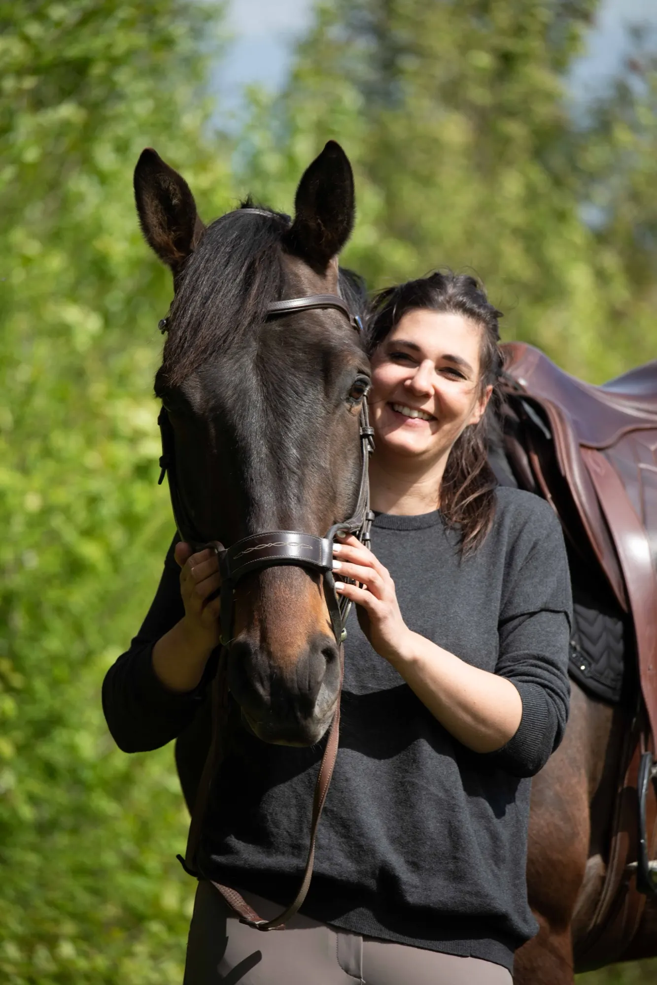 Maëva Dupertuis-Verdon souriante aux côtés d'un cheval bai sellé